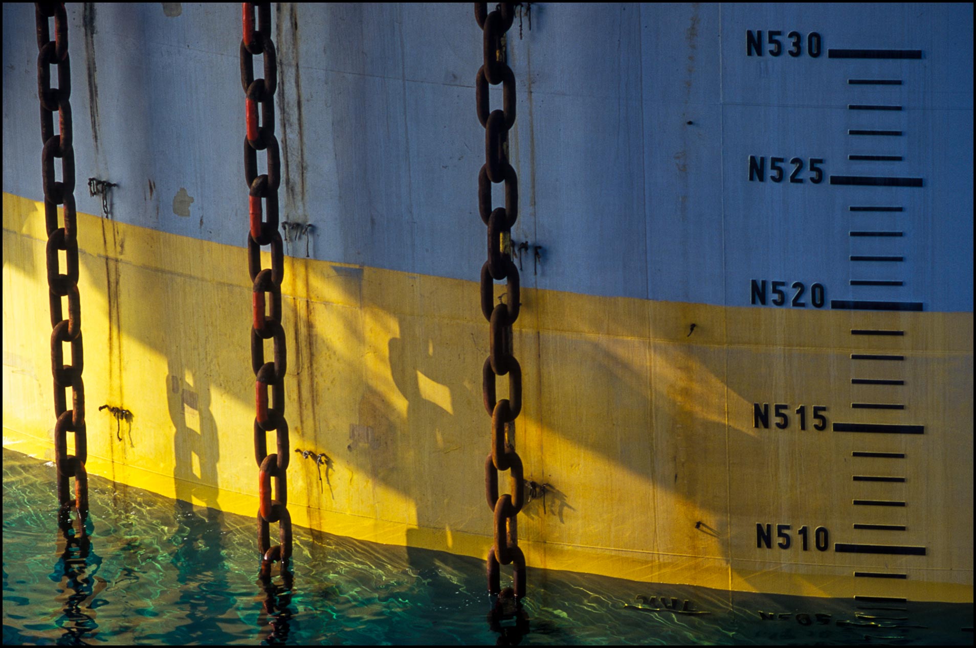 Detail of huge mooring chains fastened to ocean floor stabilize offshore rig of spar design.