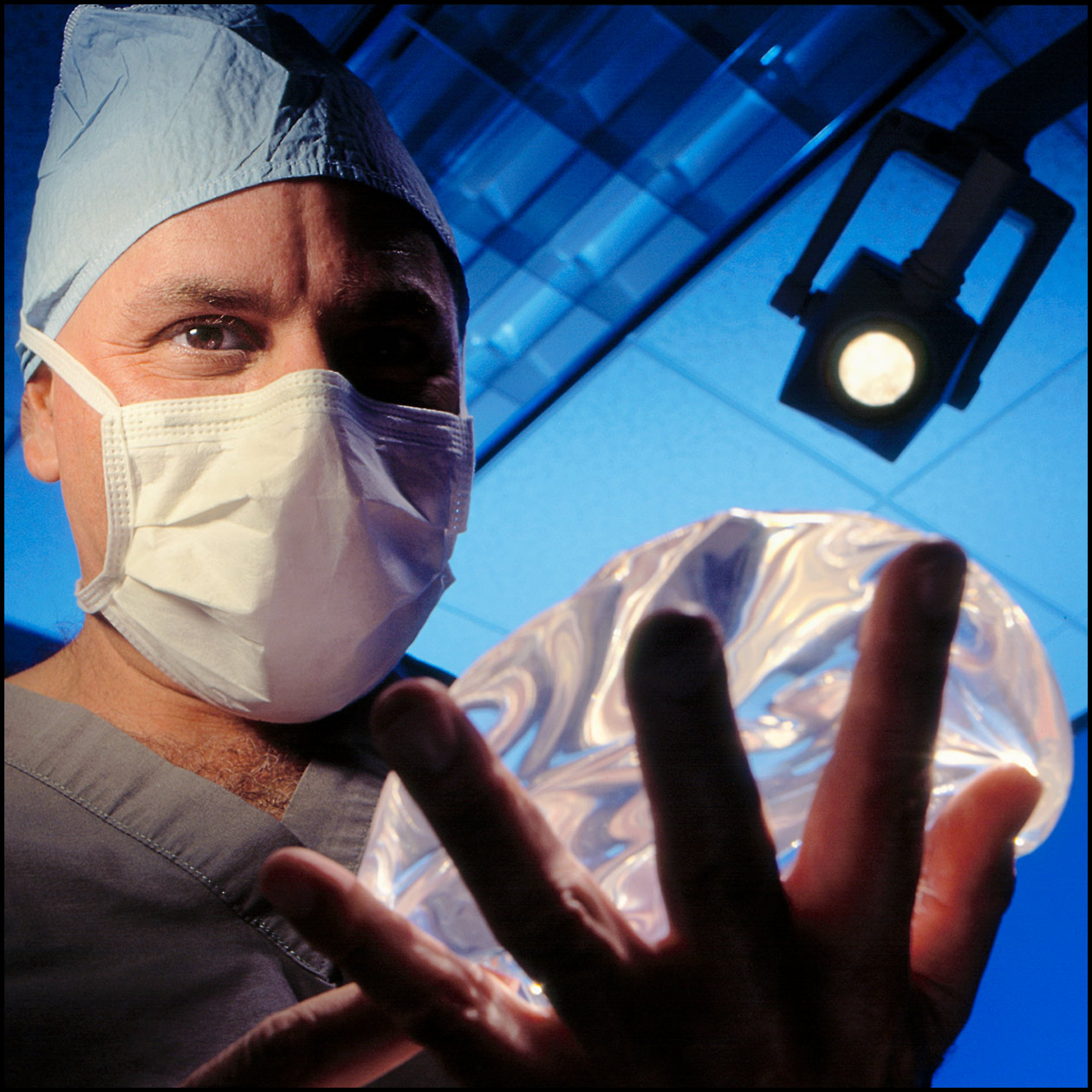 A SURGEON HOLDS A BREAST IMPLANT IN AN OPERATING ROOM  |  ROCKY KNETEN PHOTOGRAPHY