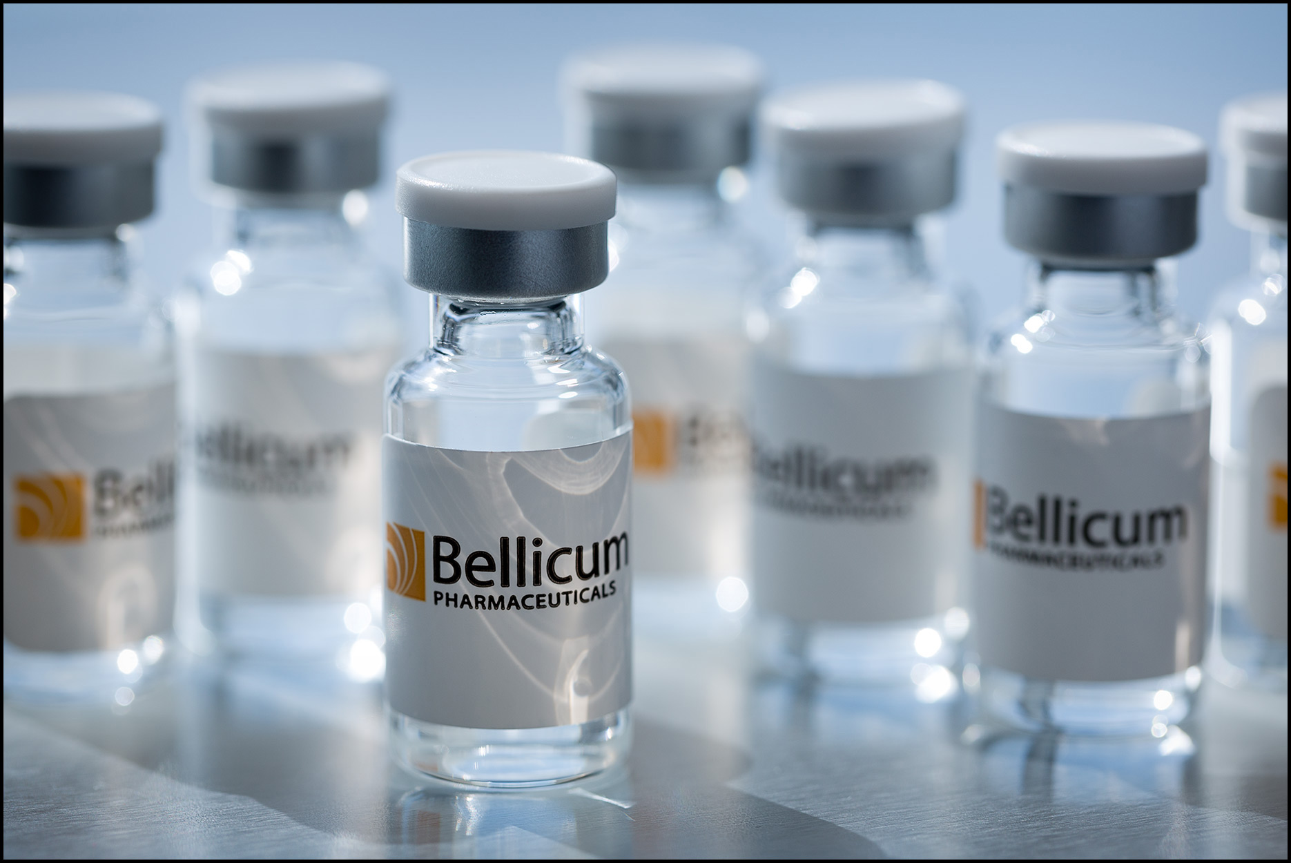 Detail of collection of small cancer drug sample vials on stainless steel surface.
