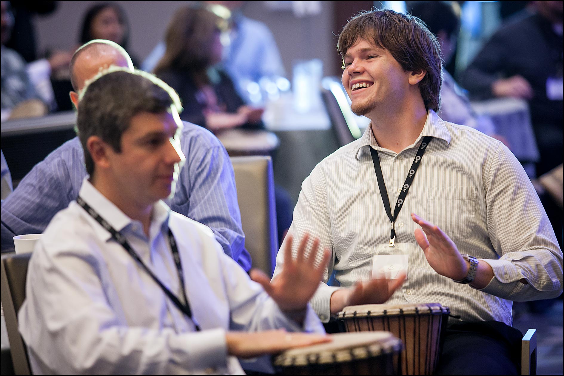 Corporate employees pound drums in a team-building exercise to begin a conference.