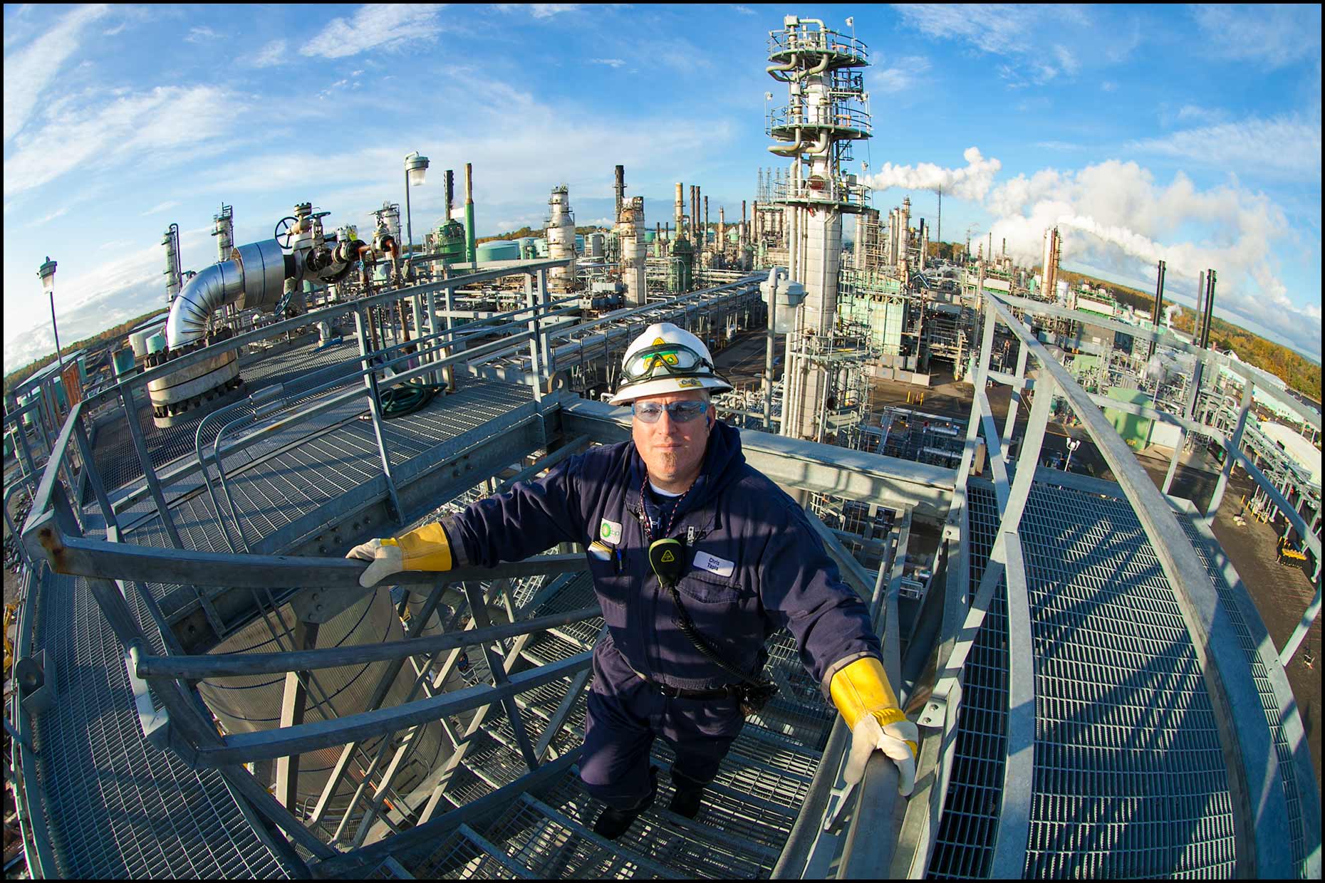 An operator on stairs at the top of a refinery unit, fisheye view.