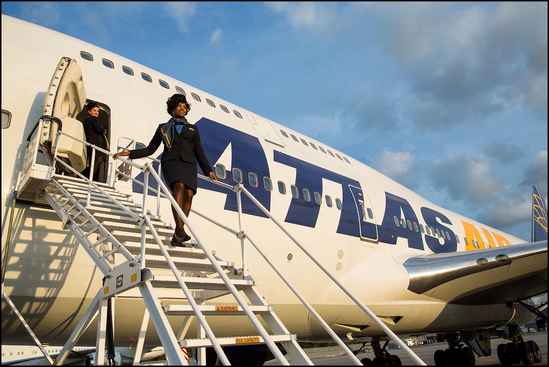 A flight attendant descends the steps of a passenger ramp of a charter jumbo jet.