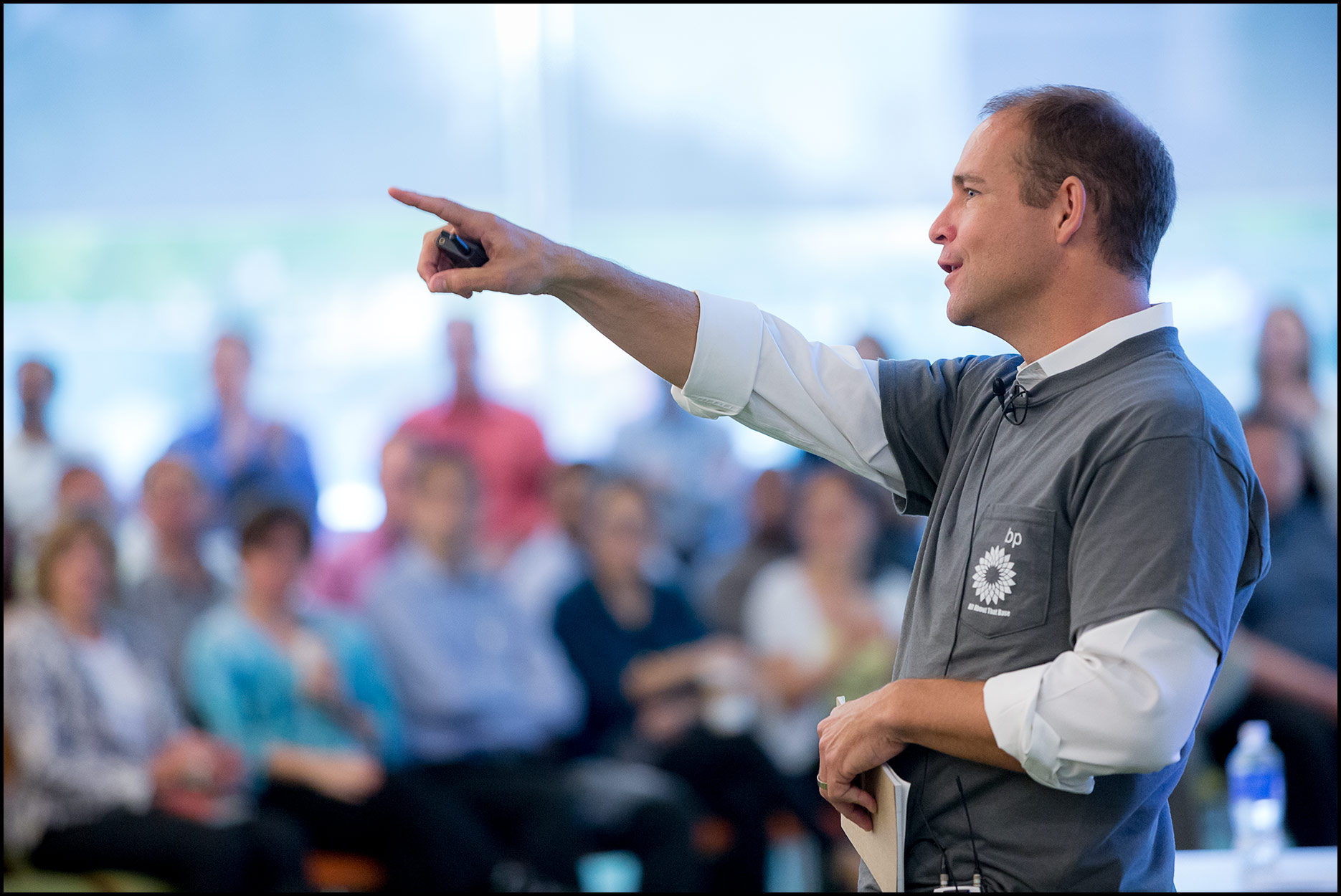 An executive in business casual dress speaks to employees in a town hall meeting.