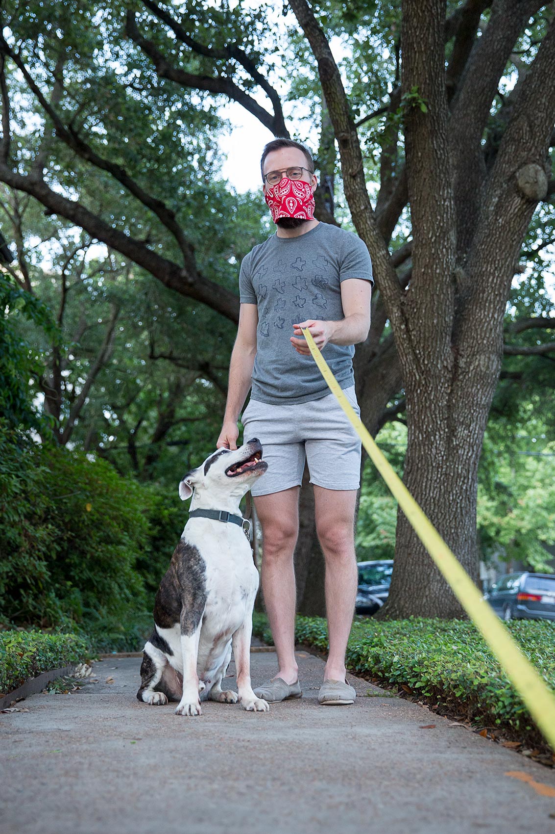 A man walking his dog holds a long tape measure as a symbol of Covid-19 social distancing